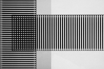 Lath structures viewed as regular stripes and checkers pattern in shades of gray. Business architecture background resembling bar codes against white stucco wall. Abstract geometric template.
