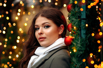 A girl with a hearing aid. The girl assumes hearing aid.Happy girl that hears well again. Holiday Concept. Decorating Christmas Tree. Beautiful  woman on christmas background.