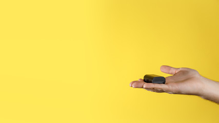 Male holds in the palm of hand black accumulator for dslr on a yellow background. Rechargeable...