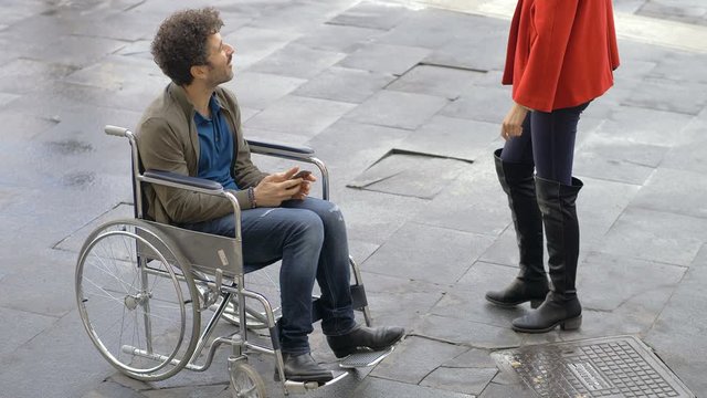 young disabled man in the city meeting his friend.She kneeling down next to him 
