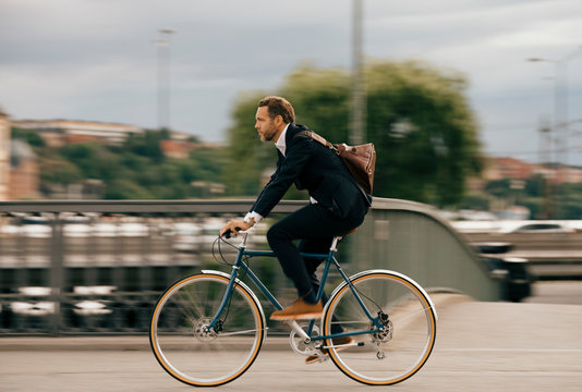 Side view of confident businessman cycling on street in city