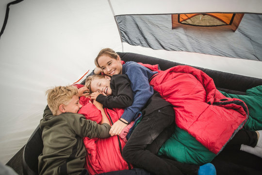 High angle view of siblings relaxing in tent