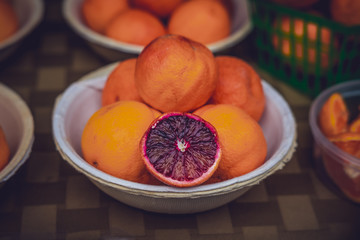 A blood orange cut in half in a pile of oranges.