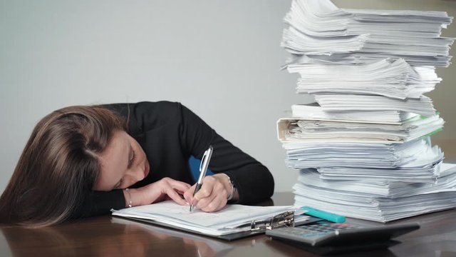 A pile of unfinished documents and files and sad businesswoman doing calculations and making notes in the office. Management work, finance accounting and deadline concept. Overloaded office worker