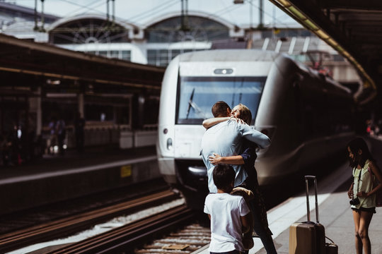 Children looking at parents embracing each other at railroad station platform
