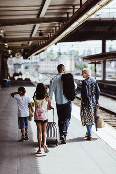 Rear view of family walking together at railroad station