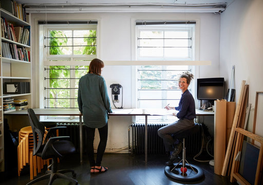 Smiling female architect with coworker at table in office