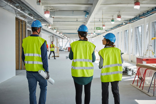 Rear view of male and female engineers walking at construction site