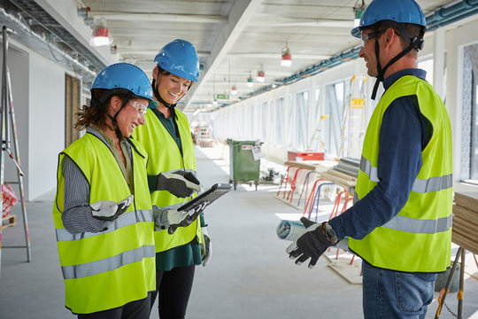 Smiling male and female architects discussing over digital tablet at construction site