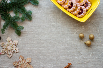 Christmas layout with space for text in the middle and cookies in a yellow vase, Nobilis branch, garland, wooden stars, cinnamon on the sides