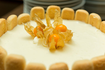 Delicious vanilla pie with physalis on the top and crackers on the sides. Tasty home made dessert. Selective focus.