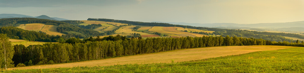 Obraz premium Panorama of colorful mountains and fields landscape illuminated by sunset.