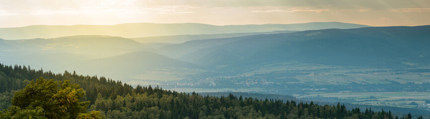 Panorama of the Sudetes, mountain peaks with a wide valley, sunny day.