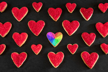 Red and rainbow heart shaped cookies on black background, distinction concept, love symbol, valentine's day pattern