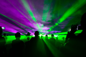 People bathed in fog and laser light, laser show.