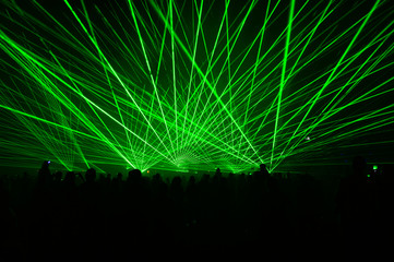 People bathed in fog and laser light, laser show.