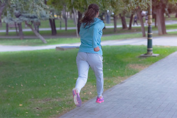 Fototapeta premium Young female woman running outdoors in urban road. Young female exercising in sport clothes.
