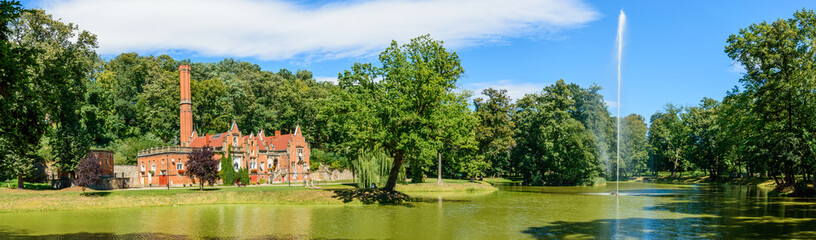 Fototapeta na wymiar A park pond with a fountain, a view of the farm building at the palace of Marianna Oranska.