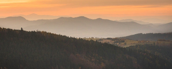 Panorama Sowie Mountains, orange sunset over the mountain valley shrouded in fog.
