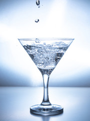 one glass of water with spray from falling water jet, white background, isolated object