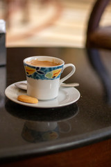 Coffee cup with biscuit on dark table.