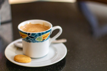 Coffee cup with biscuit on dark table.