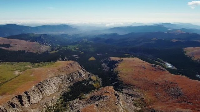 Aerial panoramic shot of the misty valley with forest and Beartrack Lake made from the top of Mount Evans, Colorado, USA