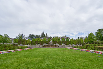 Beautiful public park in a European city with an antique fountain and green bushes, with text space