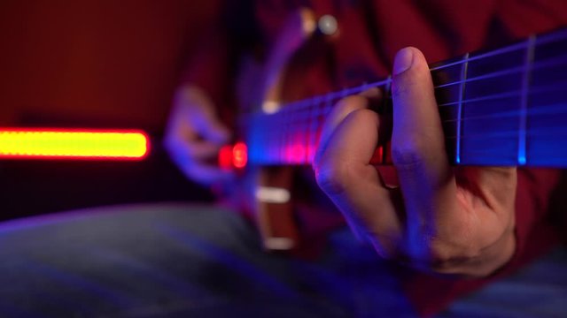 Close up of male hand fingering strings on guitar