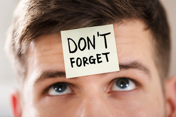 Businessperson's Forehead With Question Mark On Sticky Note