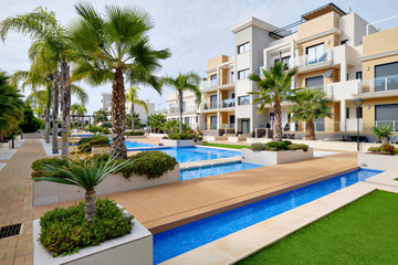 Fototapeta na wymiar Modern apartments with swimming pool cozy decorated leisure area, sunny warm day. Real estate purchasing, loan mortgage, new dwelling concept