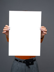 Stylish teen girl young with big paper sheet in her hands on gray background. Front view mockup...