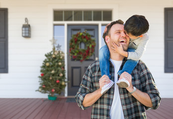 Boy Riding Piggyback on Shoulders of Father On Christmas Decorated Front Porch