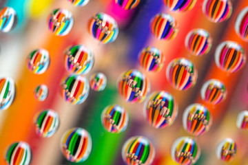 Drawing pencils reflected on waterdrops resting a piece of glass