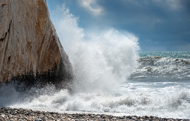Rocky seashore with wavy ocean and waves crashing on the rocks.