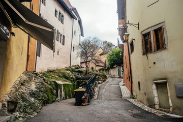 Fototapeta na wymiar Beautiful typical narrow street in small european town with vintage buildings on cloudy sky background. Photography with old houses facades.