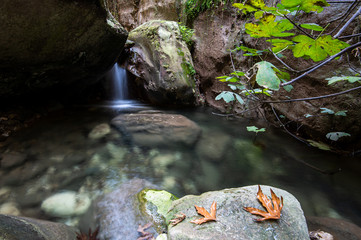 Idyllic calm lake with blue clean water and small waterfall flowing between the rocks.