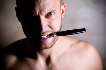 man holding a knife in his teeth