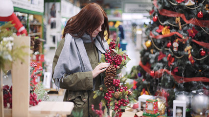 A young beautiful woman walks around the store and selects Christmas decorations and decorations to celebrate the New Year. New year shopping 