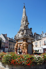Fototapeta premium Ville de Noyon, Fontaine du Dauphin (XVIIIe siècle) entourée de fleurs rouges et blanches, département de l'Oise, France