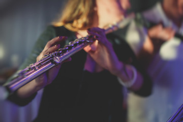 Concert view of a flutist flute player with musical jazz band and audience in the background