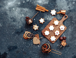 Homemade Christmas star shape gingerbread cookies with frosting and cinnamon over cutting board. Top view, flat lay