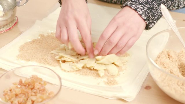 Woman's hands putting apples over phyllo dough to make Viennese strudel