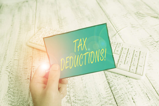 Writing note showing Tax Deductions. Business concept for reduction income that is able to be taxed of expenses Man holding colorful reminder square shaped paper wood floor