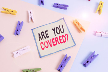 Conceptual hand writing showing Are You Covered Question. Concept meaning asking showing if they had insurance in work or life Colored clothespin paper reminder with yellowblue background