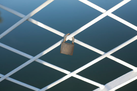 A padlock locked around the bridge fence