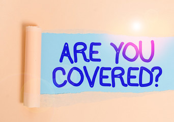 Handwriting text Are You Covered Question. Conceptual photo asking showing if they had insurance in work or life Cardboard which is torn in the middle placed above a plain table backdrop