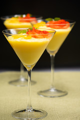 Vanilla Pudding with lemon and strawberry garnish in Martini glass with black background.