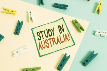 Conceptual hand writing showing Study In Australia. Concept meaning going into foreign country order complete your studies Colored clothespin paper reminder with yellowblue background