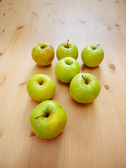 Group of seven green apples on a wooden table